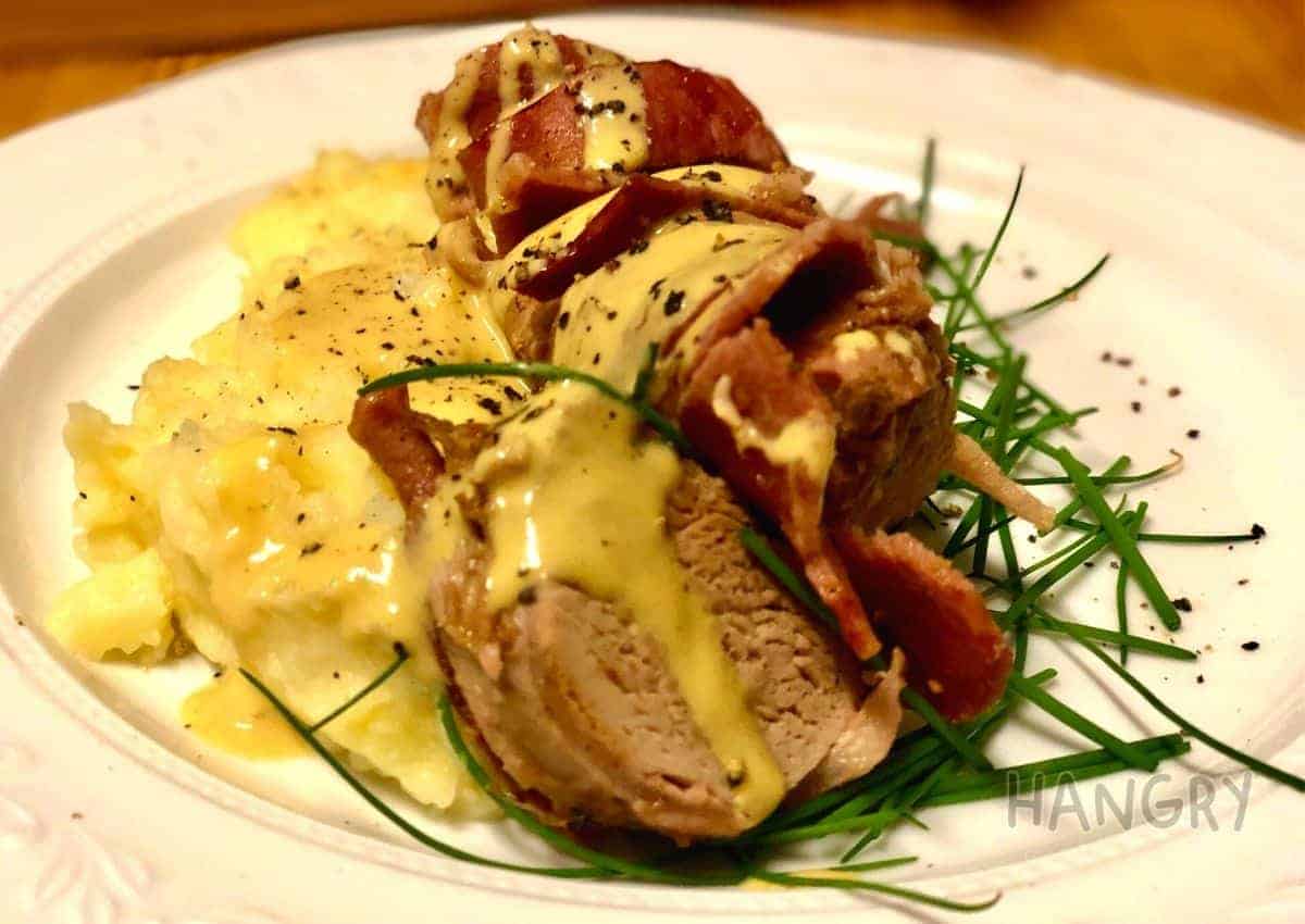 Bacon wrapped pork fillet served on a bed of mustard mash